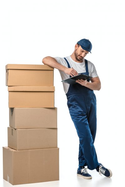 mover in uniform writing in clipboard near cardboard boxes isolated on white